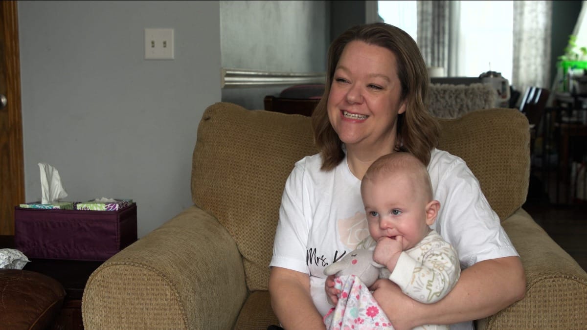 Karen Rieck holds her baby on a couch.