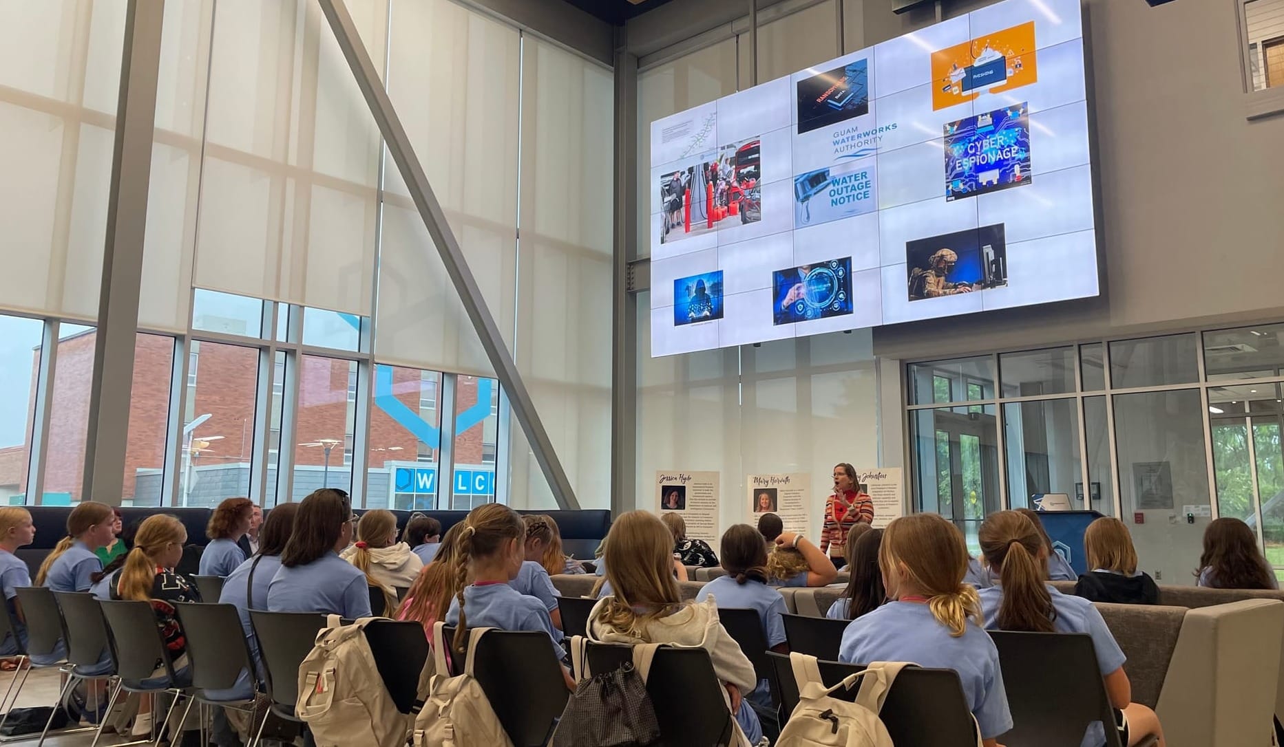 A group of students wearing blue shirts watches a presentation at the CybHER camp at Dakota State University.