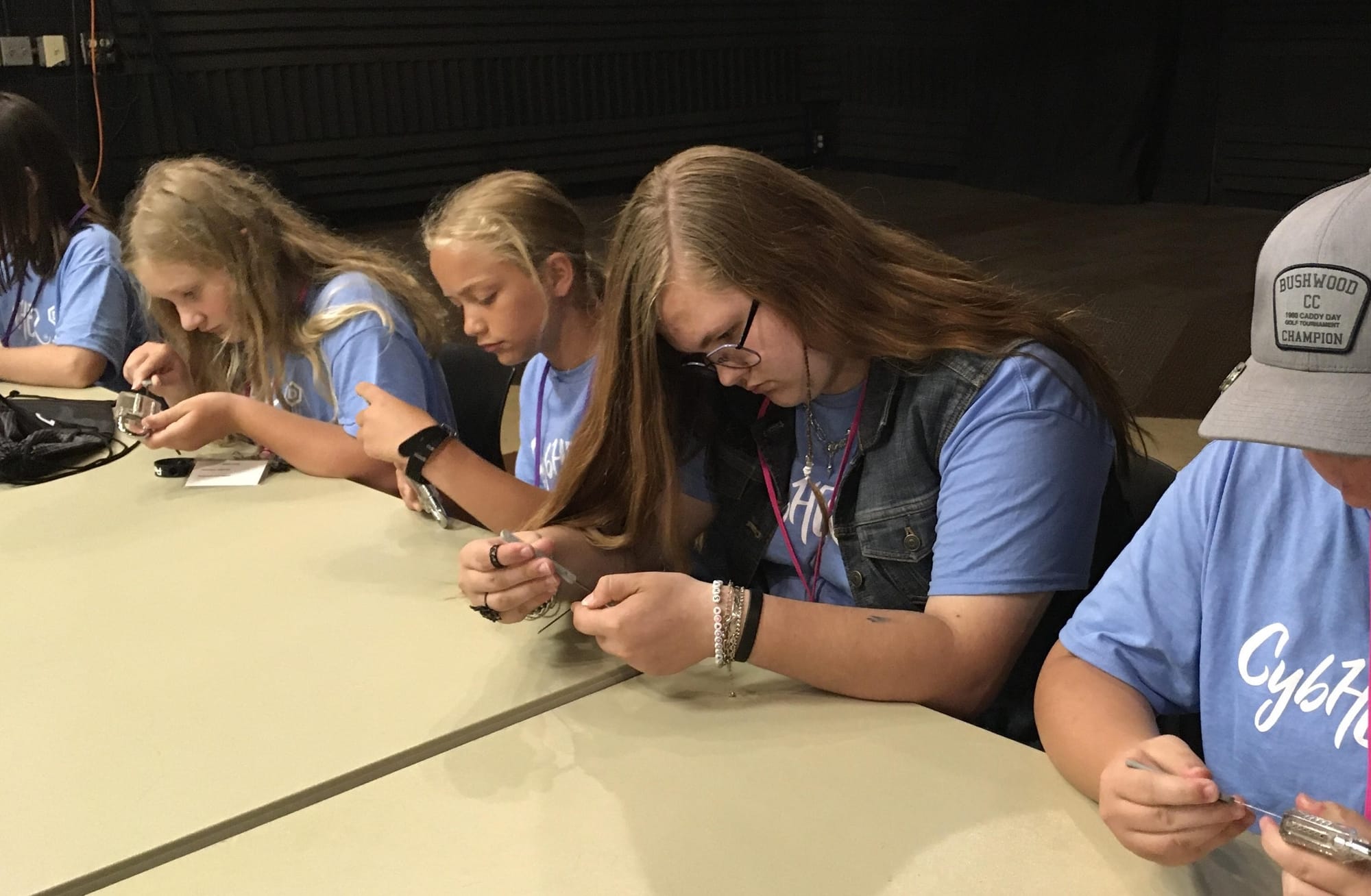 A group of girls pick a lock while seated at the CybHER camp at Dakota State University