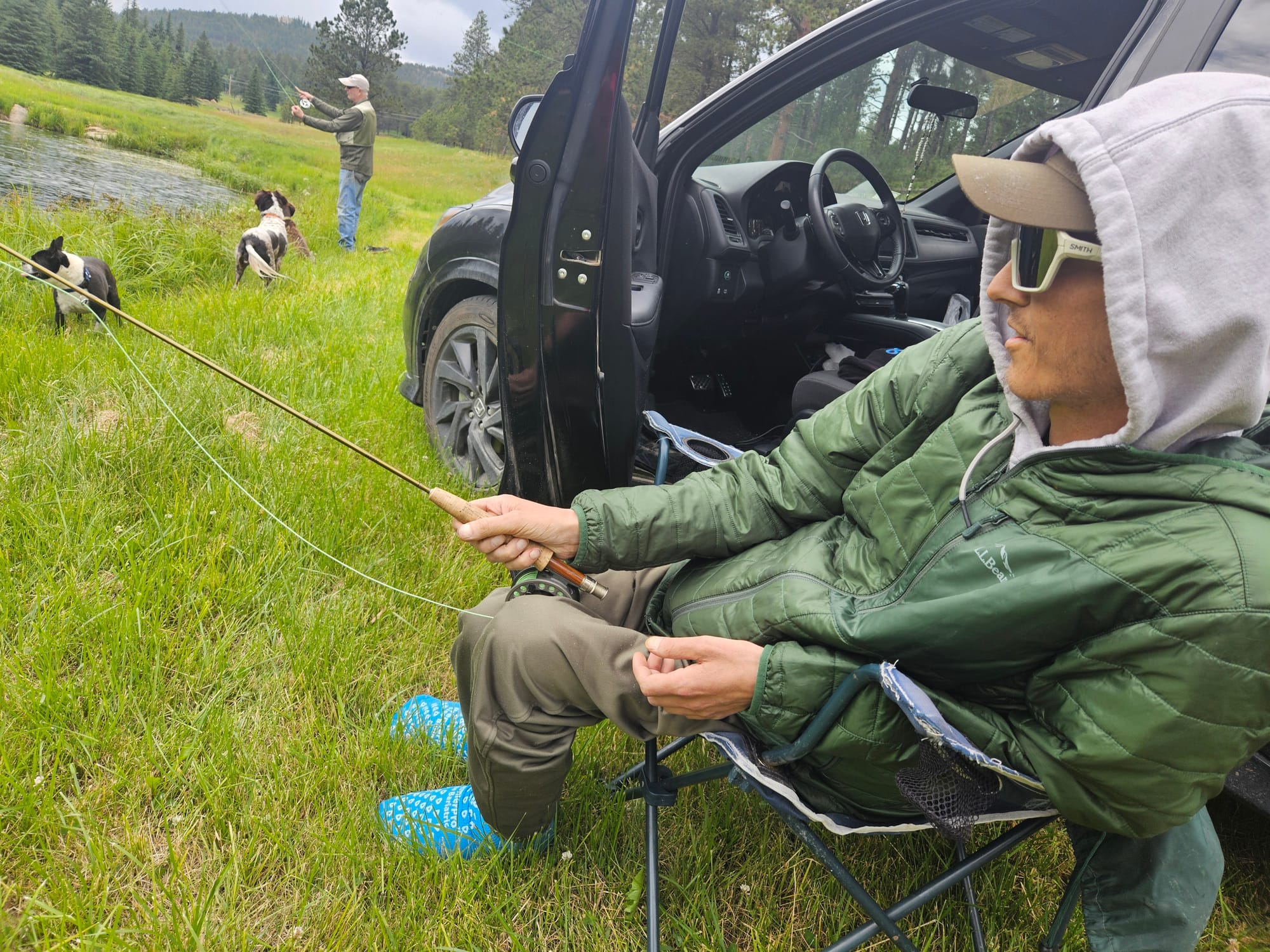Taylor Nielsen and his dad, David Nielsen fly fish in the Black Hills. Two dogs are running in the foreground.