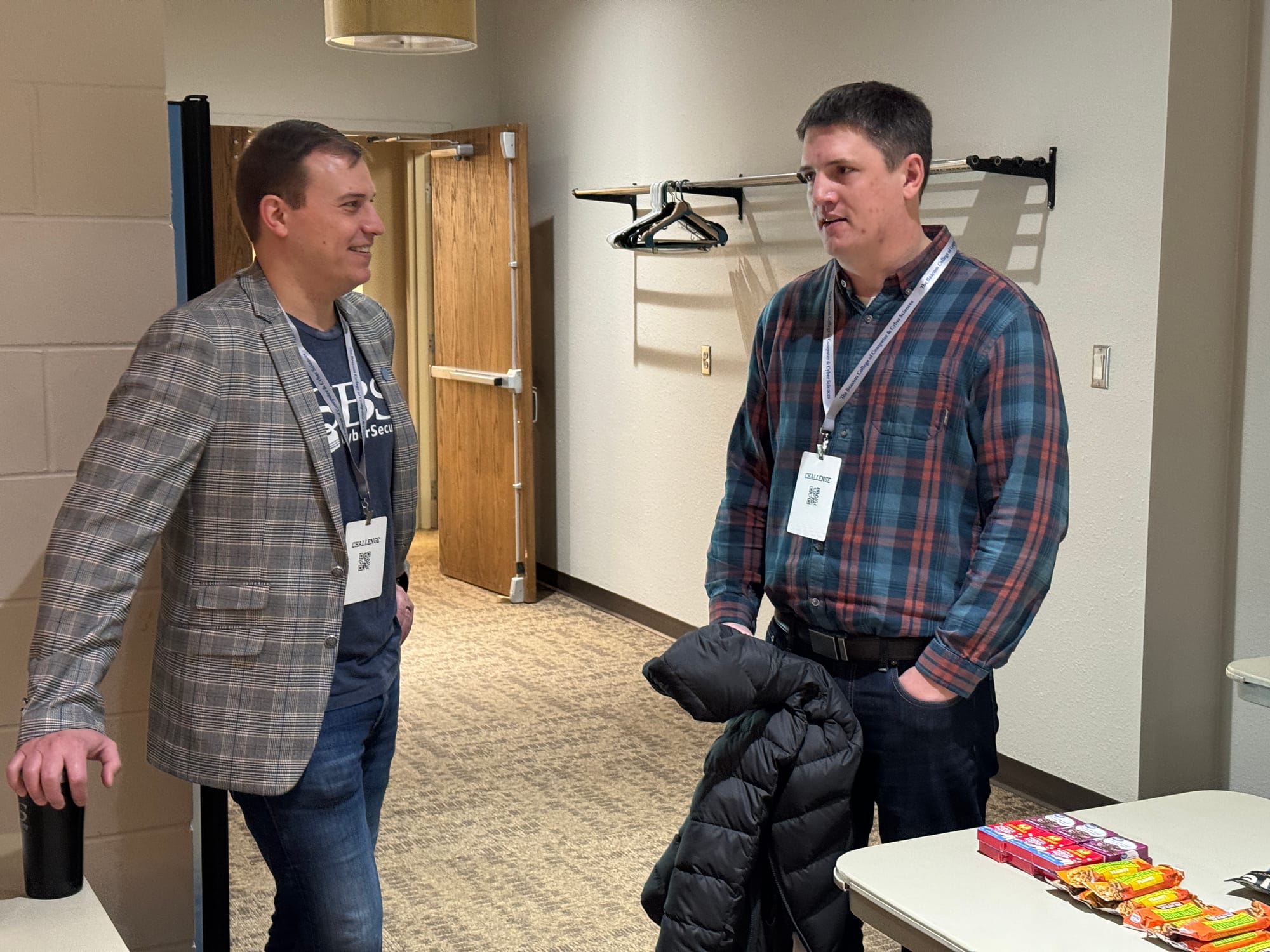 Two men stand in a hallway talking at a Dakota State University event