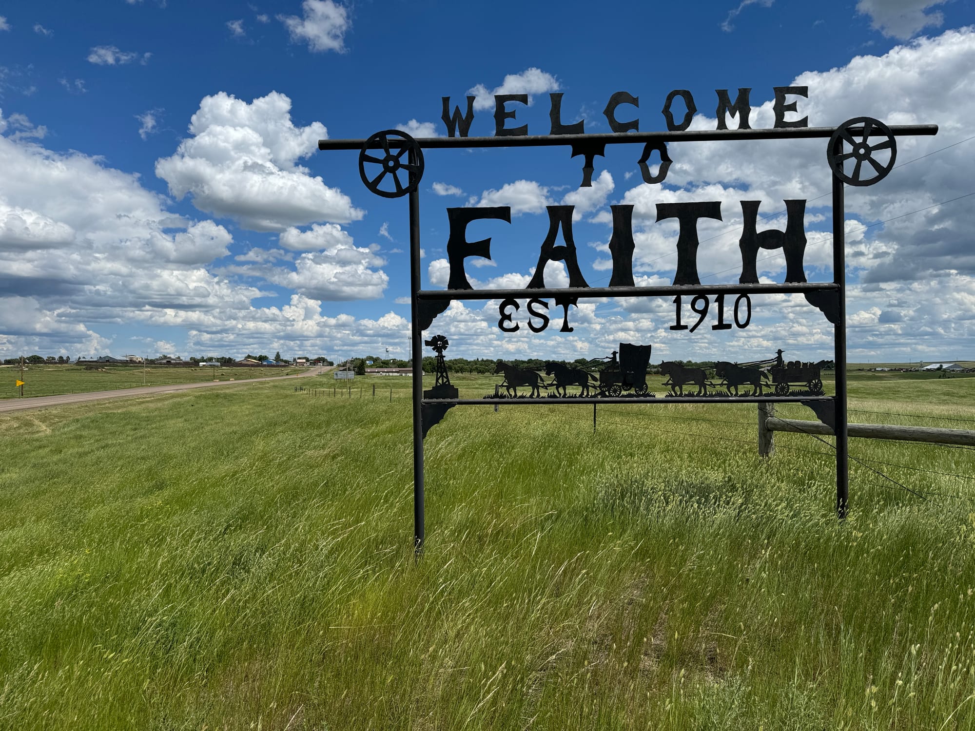 A Welcome to Faith sign is shown in the prairie of South Dakota.
