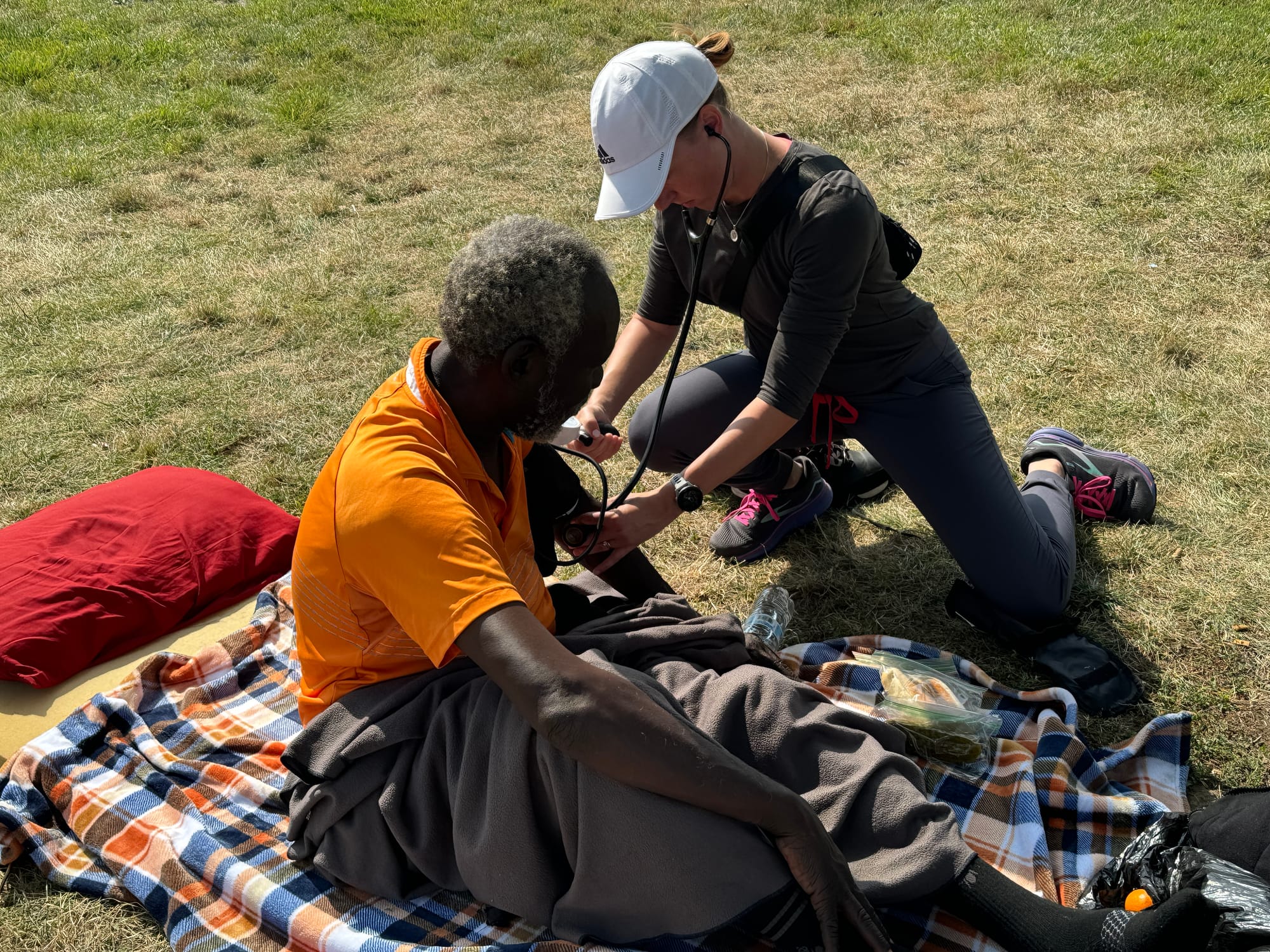 A physician takes the blood pressure of a homeless man on a patch of grass in Sioux Falls.