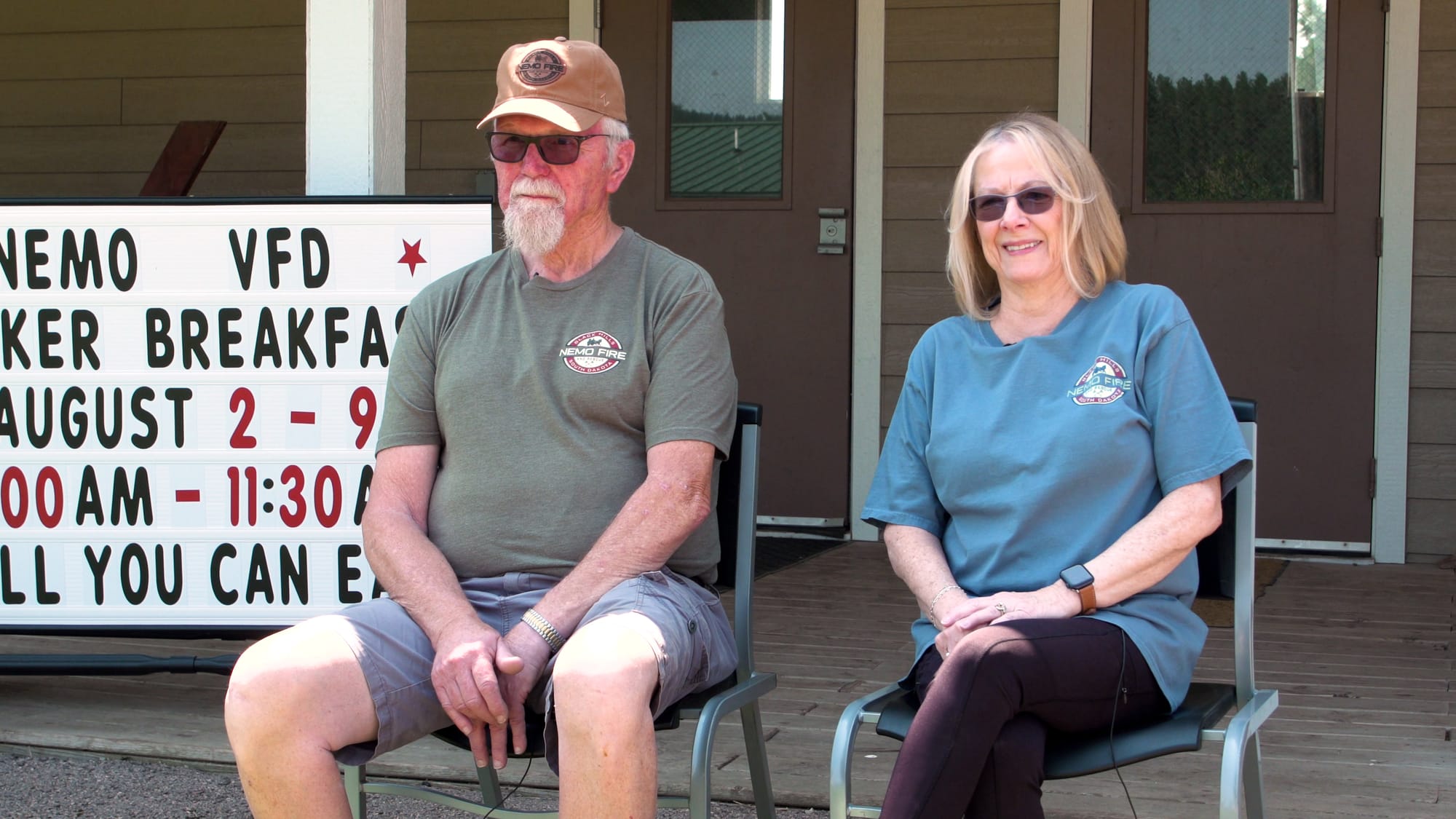 A man and a woman sit outside a building where they serve motorcyclists an all-you-can-eat breakfast.