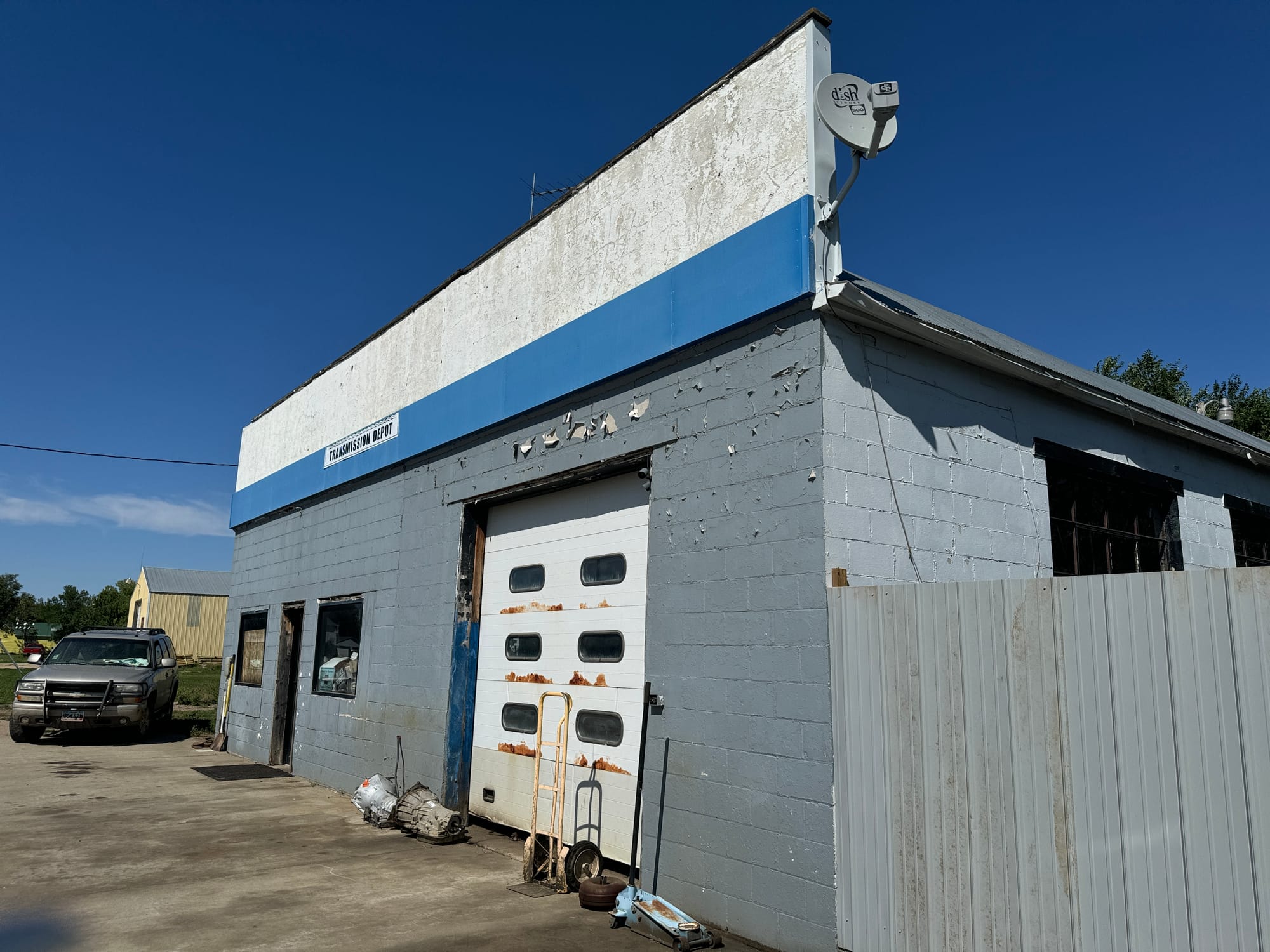 A gray metal fence is shown next to an auto repair shop in Armour, South Dakota.