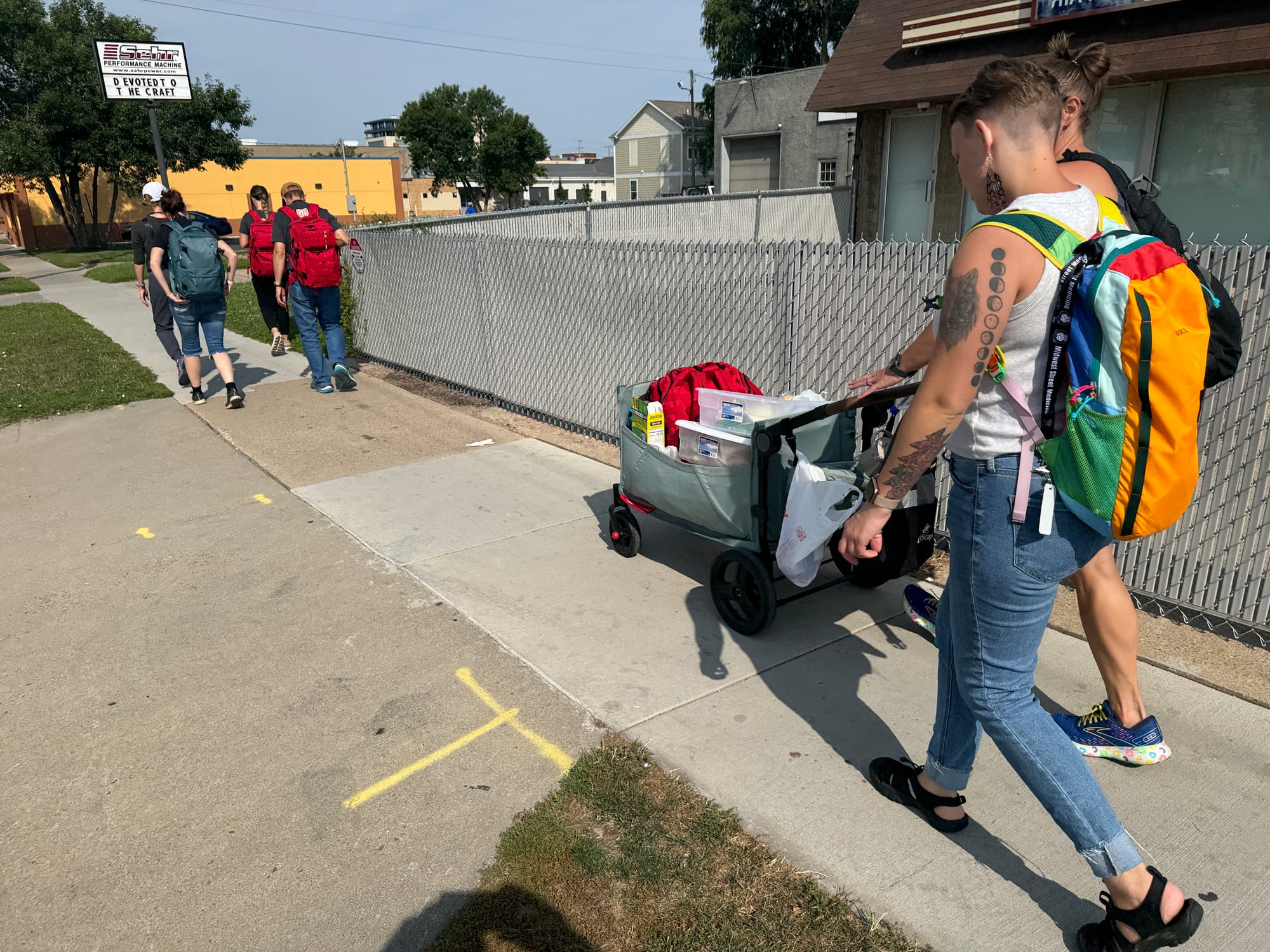 One crew of medical volunteers with Midwest Street Medicine  walk down a sidewalk with their supplies while looking for potential patients.