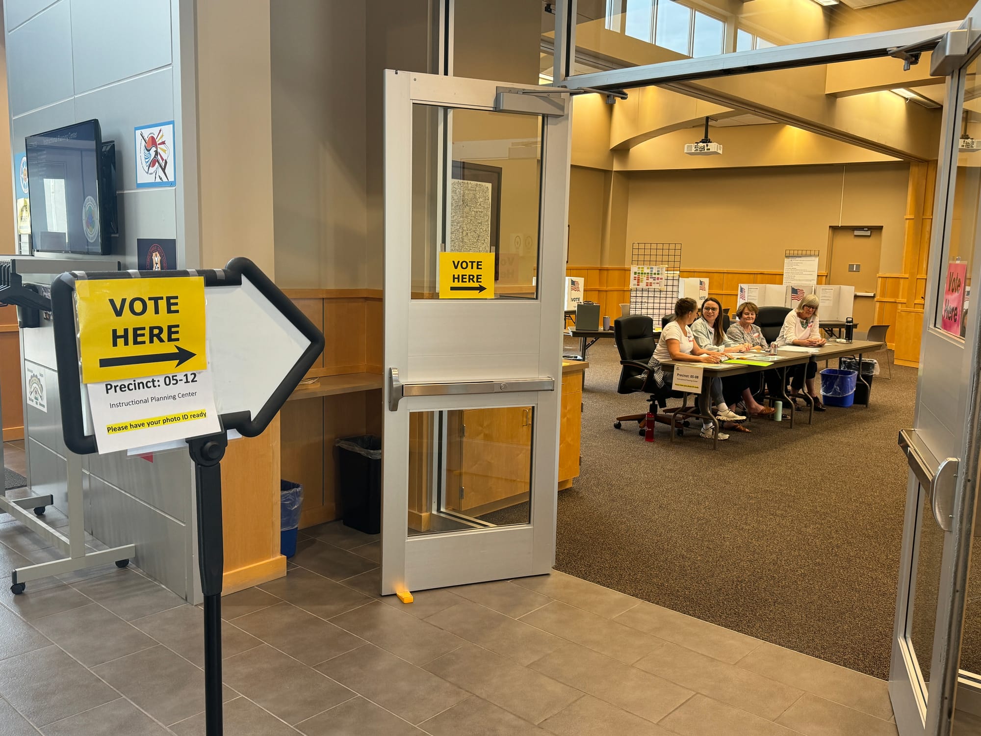 Poll workers sit at a table waiting for people to cast votes during an election