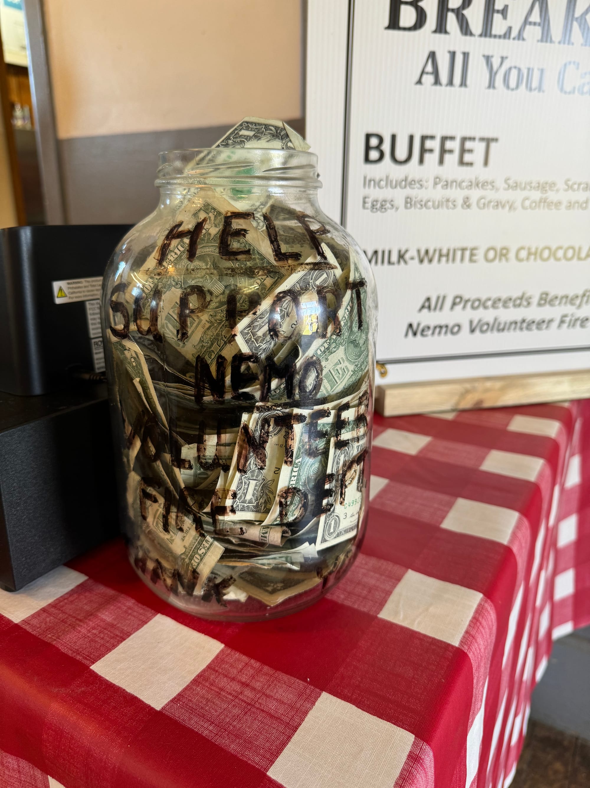 Dollar bills inside a tip jar on a table. 