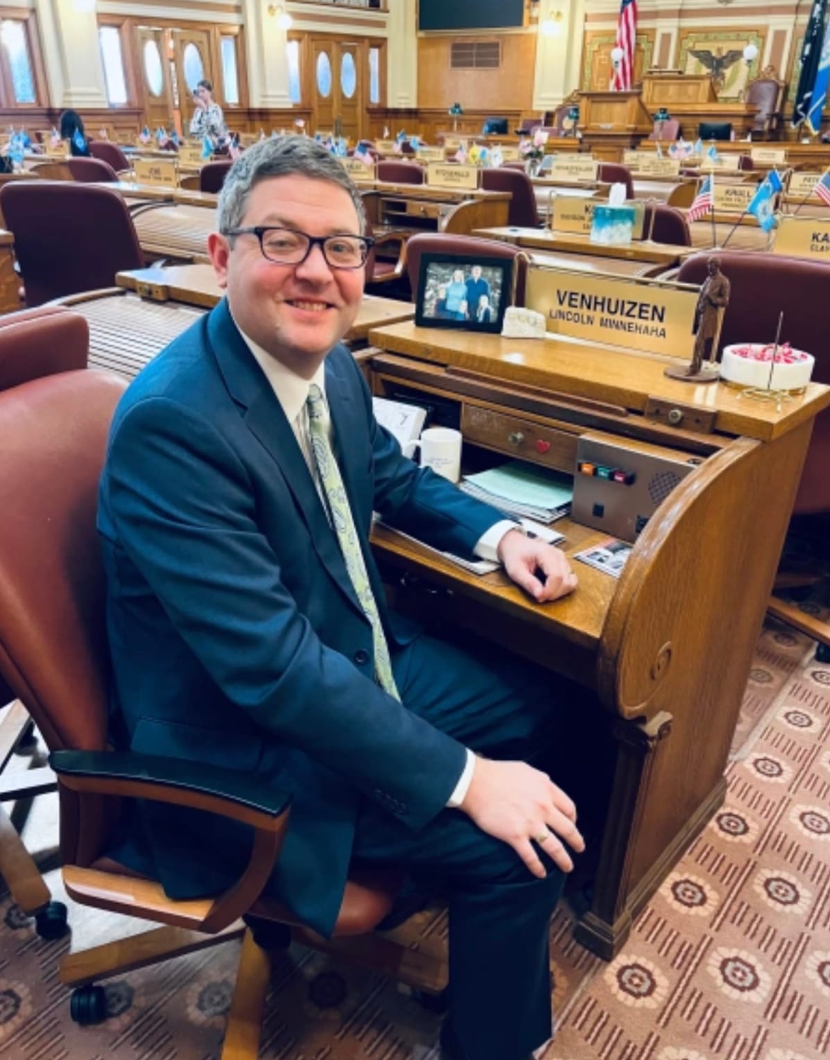 State Rep. Tony Venhuizen, a Sioux Falls Republican, sits at a desk and looks at the camera at the South Dakota capitol.