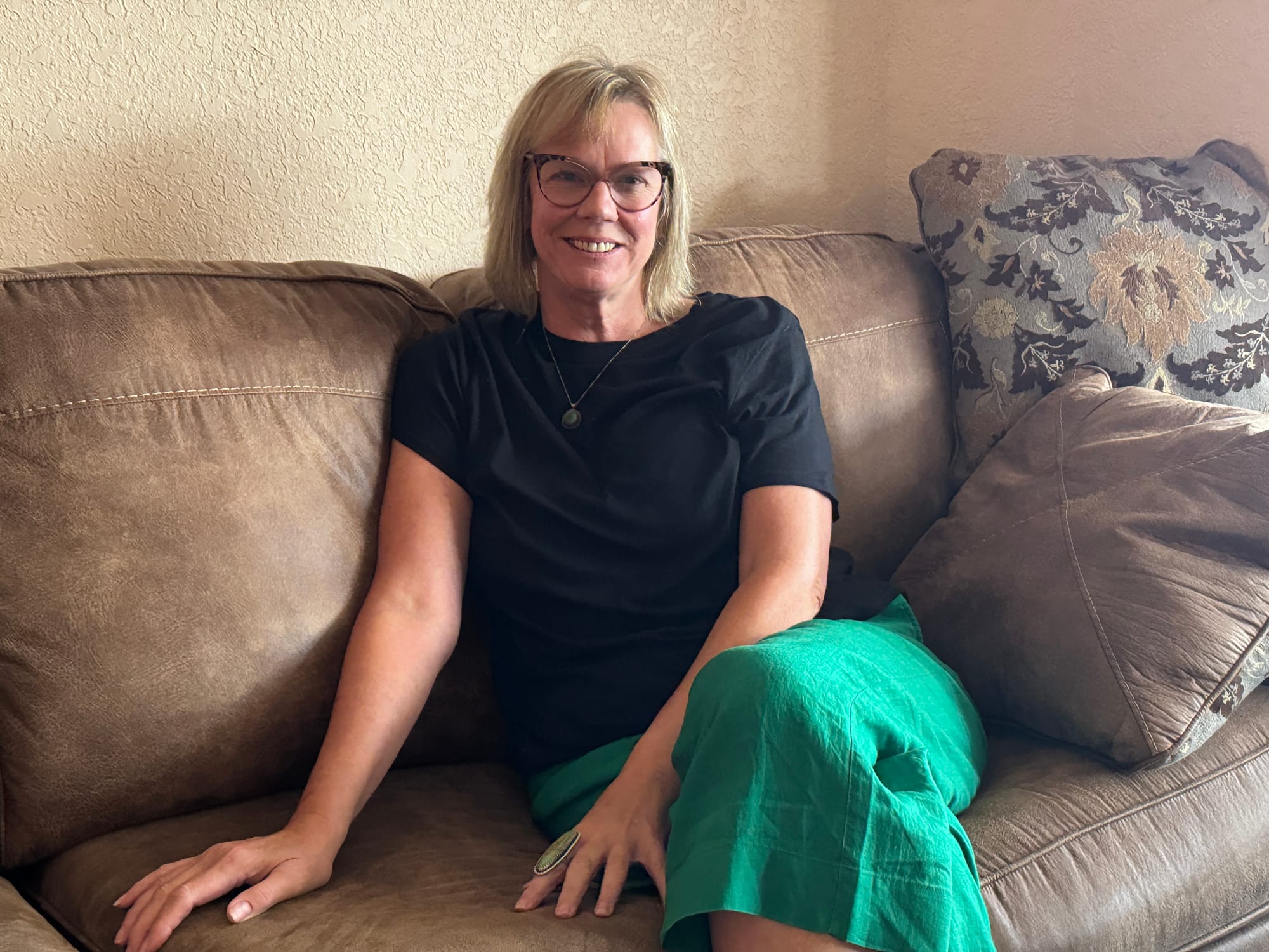 Andrea Powers poses for a photo on a couch while looking at the camera.