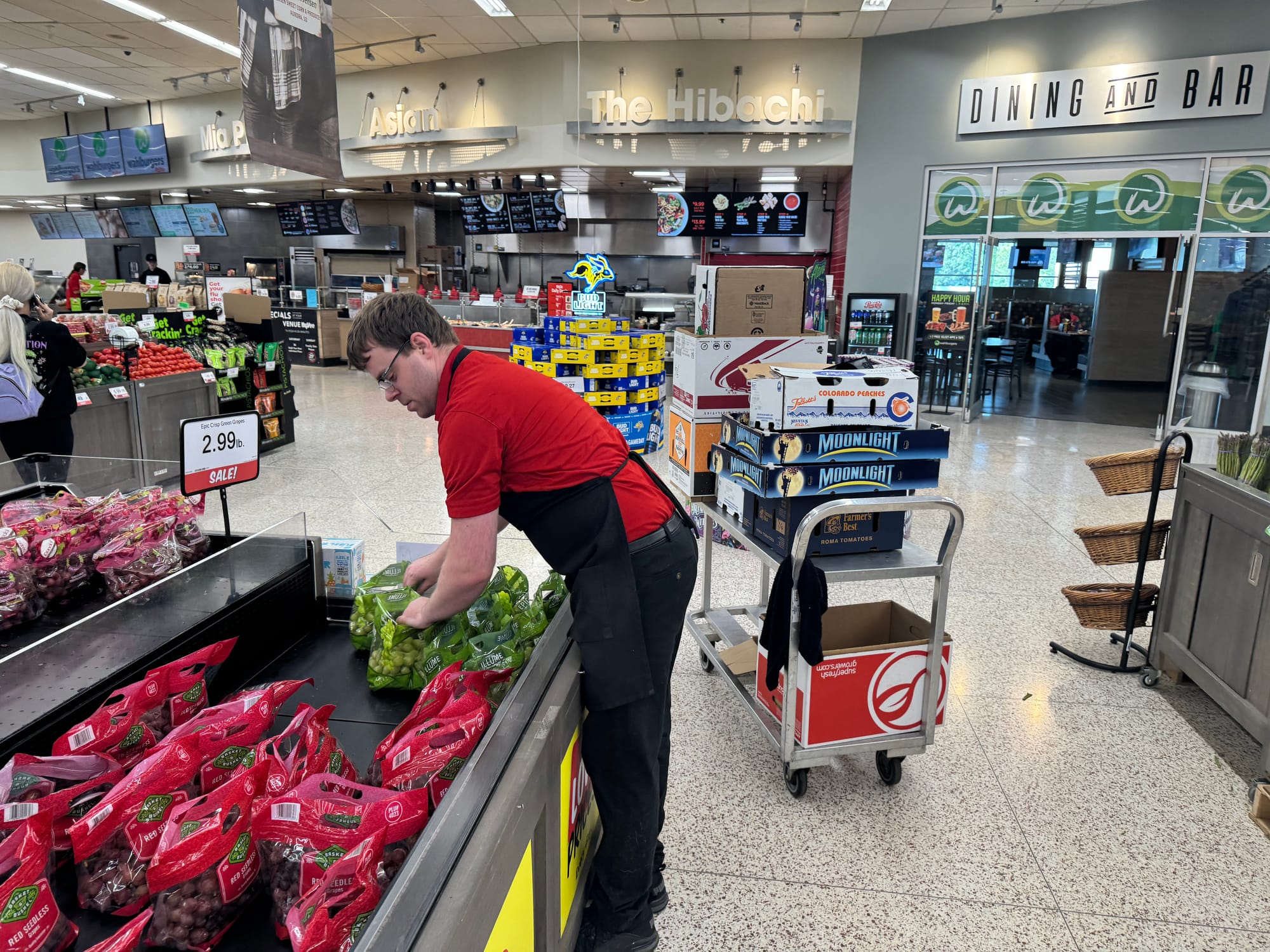 A Hy-Vee employee puts grapes on display at the 26th Street location in Sioux Falls, S.D.