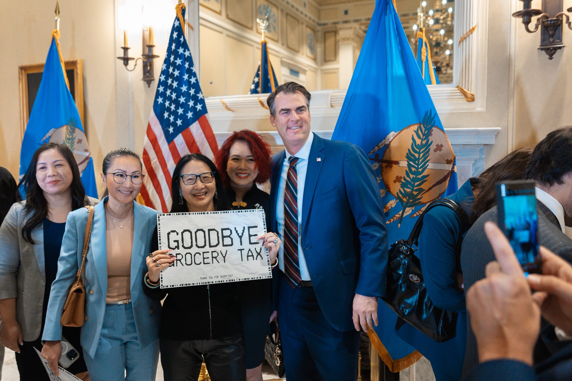 Oklahoma Gov. Kevin Stitt poses with supporters on Feb. 27, 2024, in Oklahoma City after signing a bill to eliminate the state’s 4.5% sales tax on groceries. 