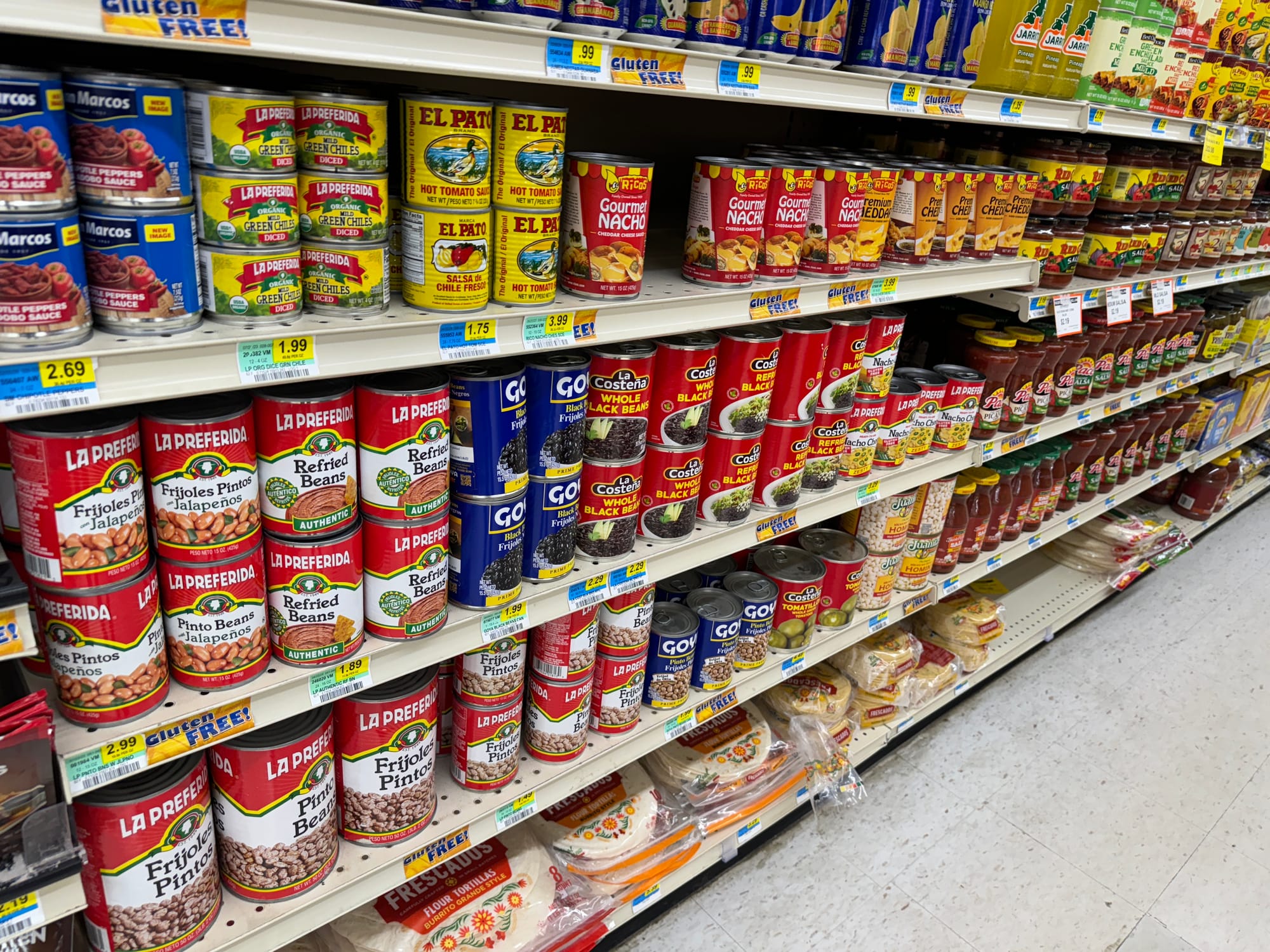 Canned groceries are lined up on shelves at a grocery store.