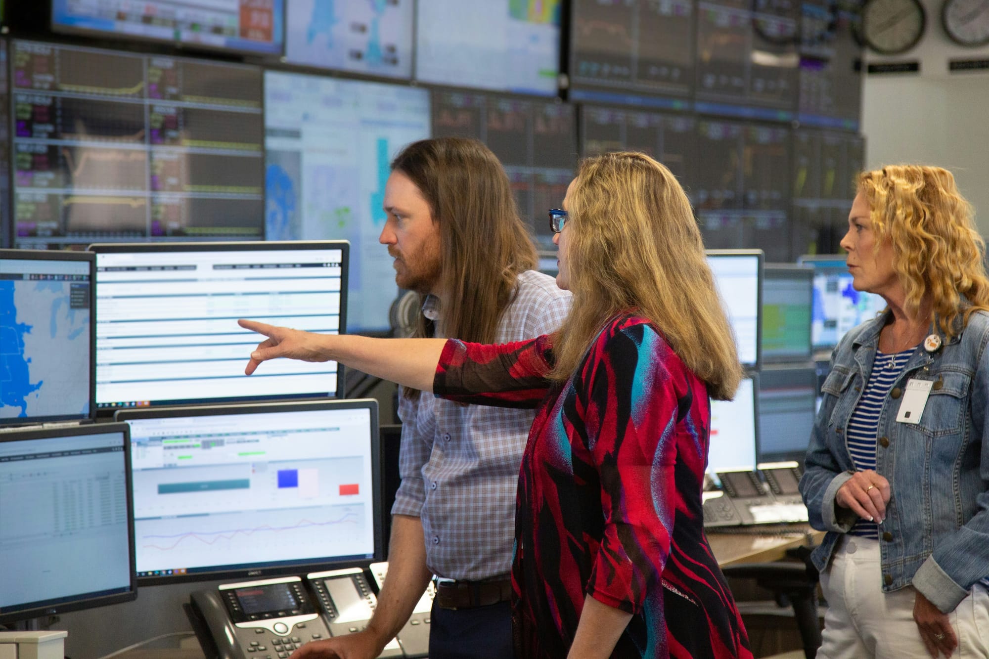 Kristie Fiegen points at a monitor in an operations room of an energy plant