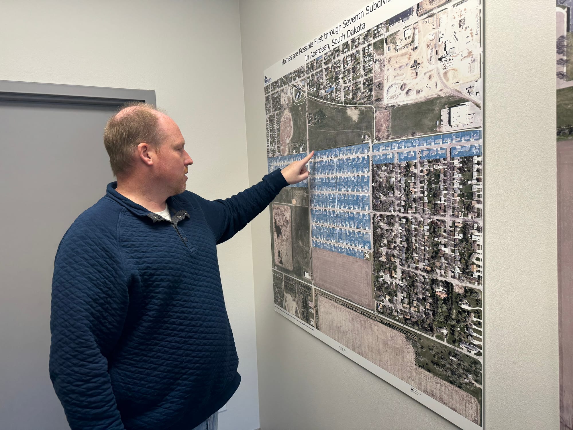 Darin Beckius, executive director of Homes Are Possible Inc., points at a map of homes on a wall