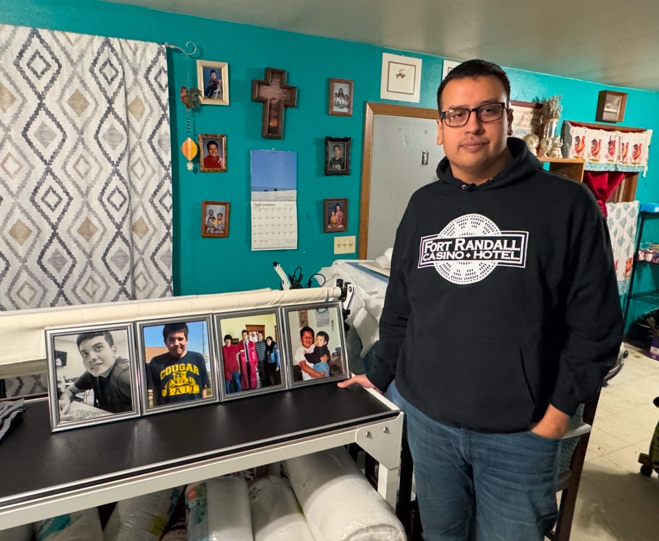 Zane Zephier, of Harrisburg, S.D., poses with portraits of his late brother, Zander, on Dec. 11, 2024, in the tribal housing community just north of Wagner, S.D.