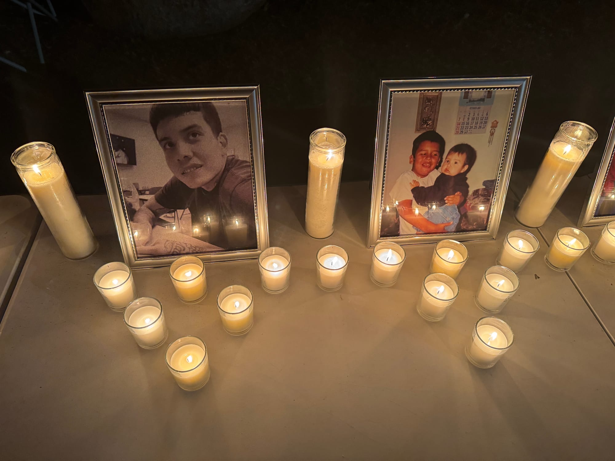 Portraits of Zander Zephier are surrounded by lit candles during a vigil held