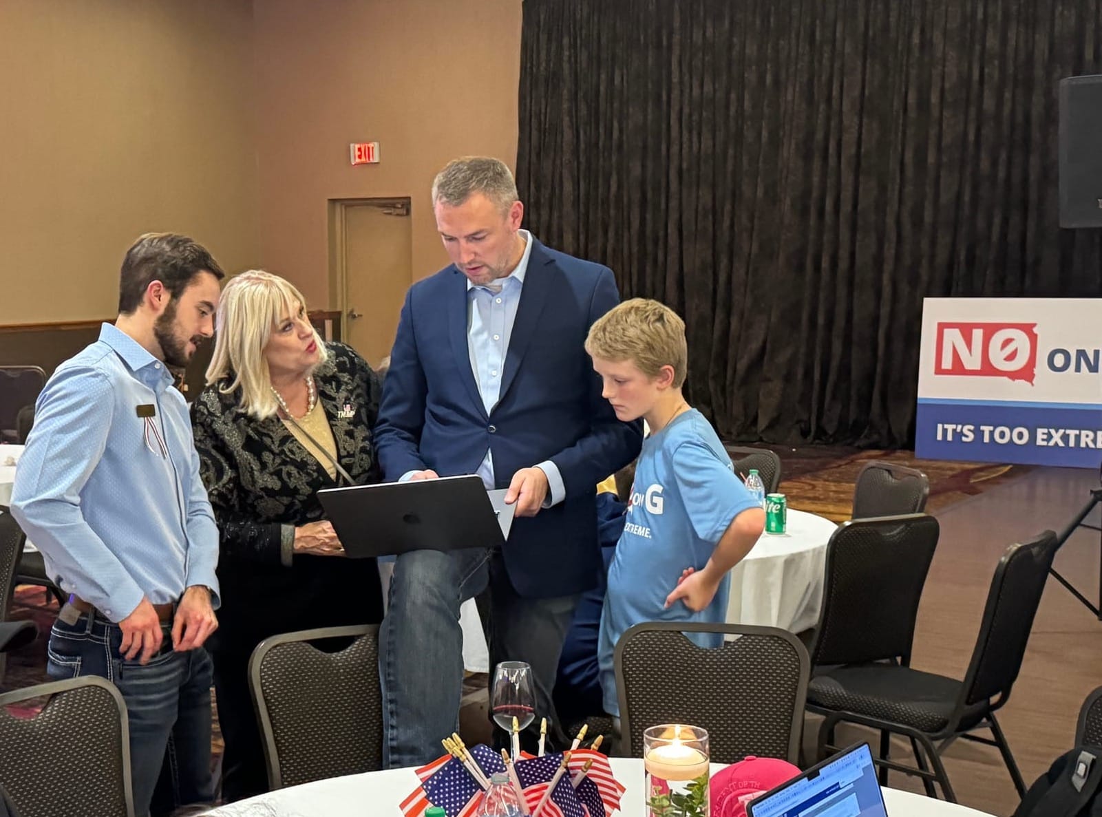 A group of politicians and their family look at a computer that shows election results