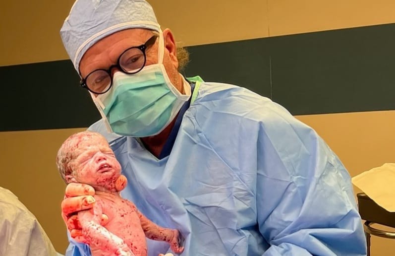 A doctor holds a newborn right after birth