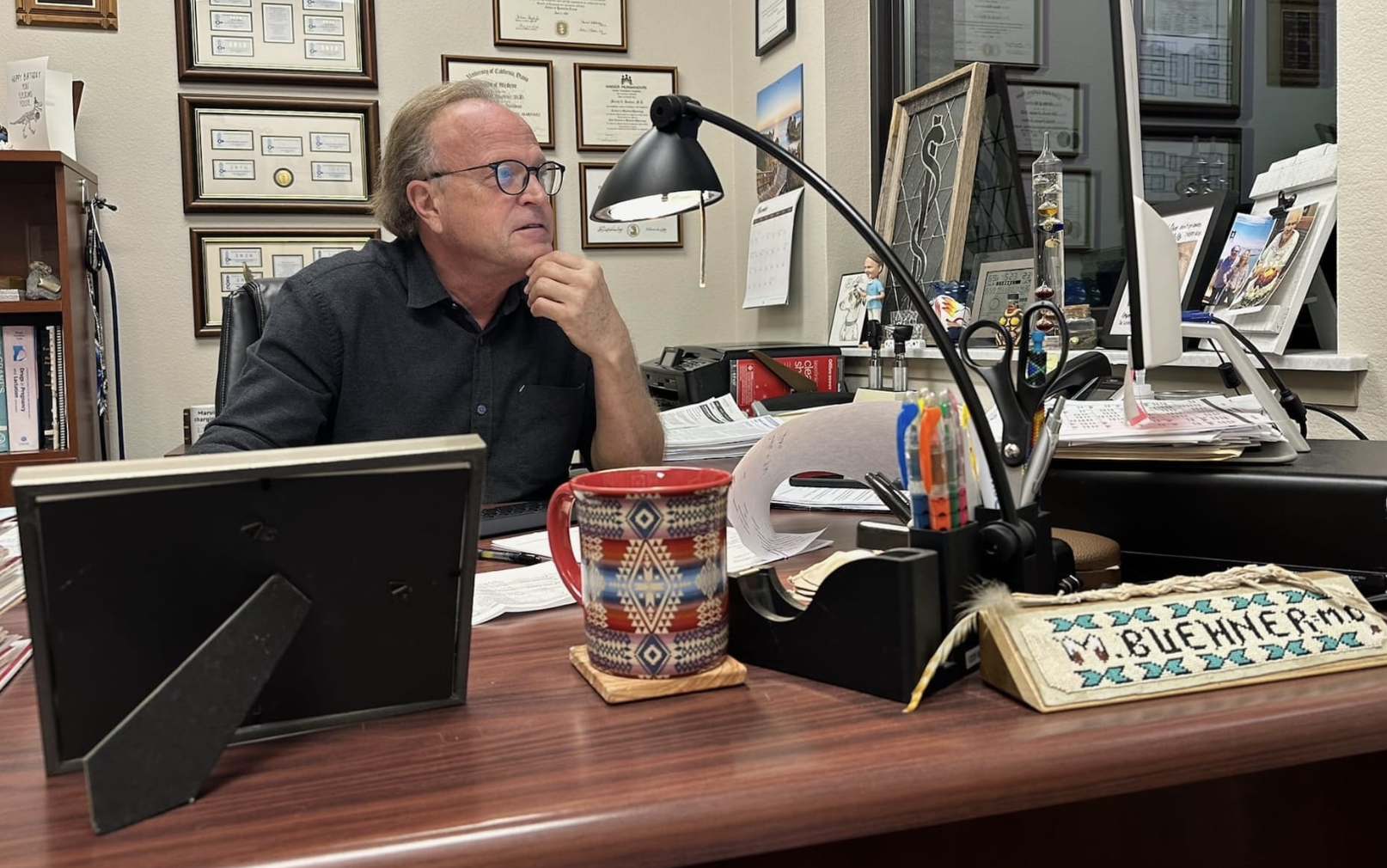 A doctor sits at his desk in his office