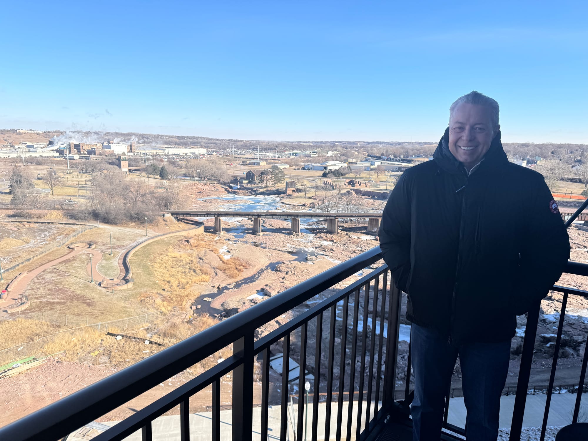 Greg Sands poses from a seventh-floor balcony at the Canopy by Hilton overlooking Falls Park in Sioux Falls