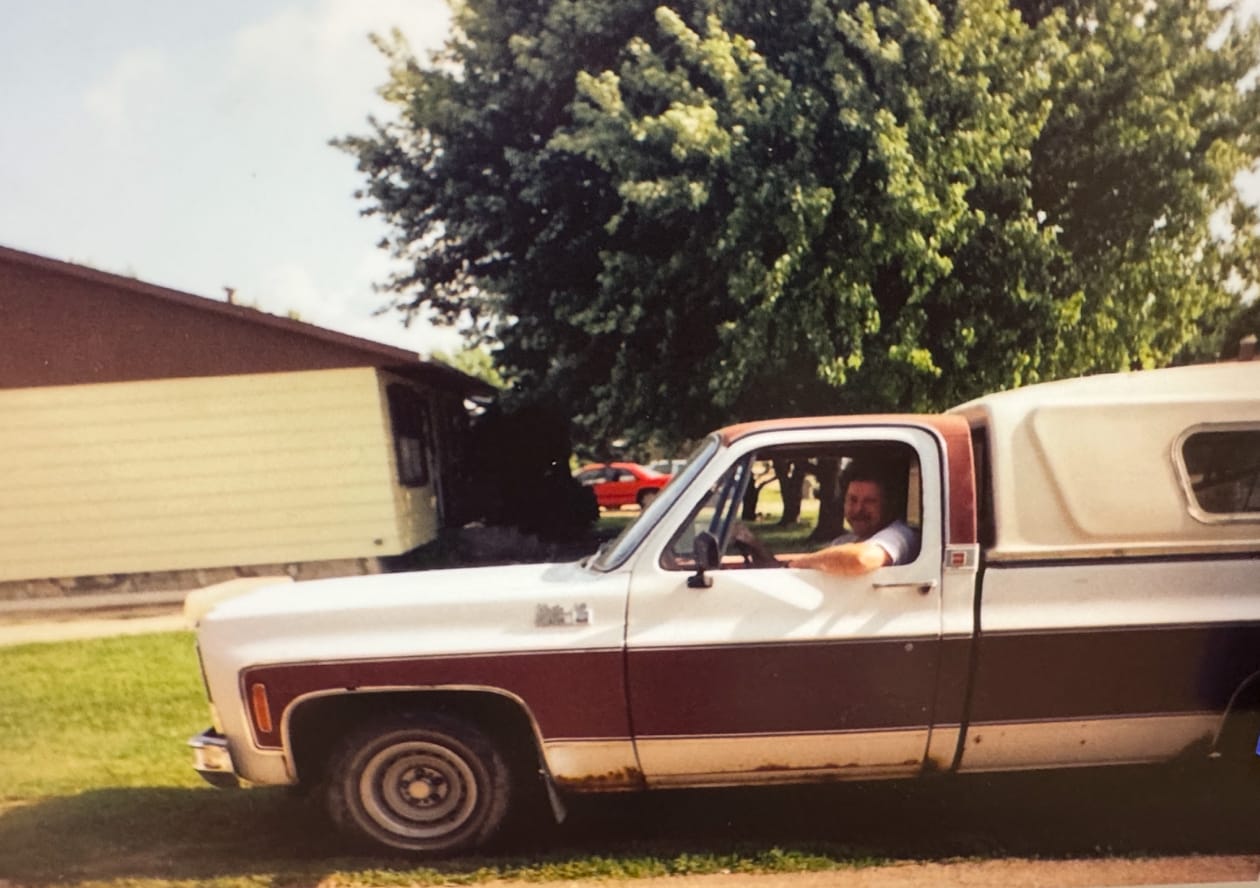 Greg Sands sits in a 1973 pickup truck outside of a house