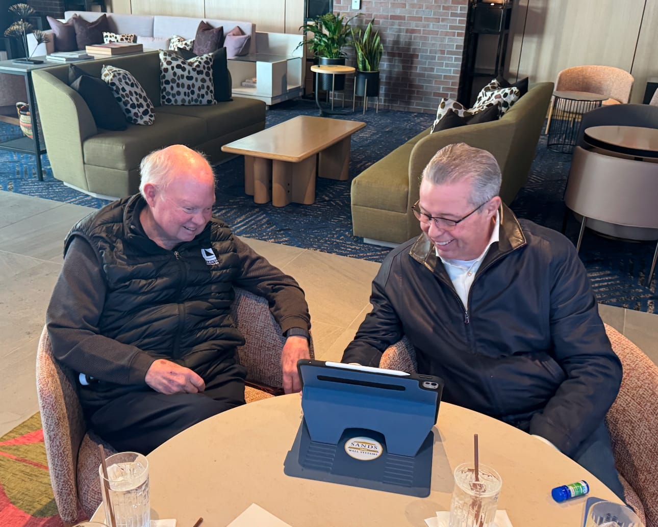 Lloyd Companies founder Craig Lloyd (left) reminisces with Greg Sands at a table in an office complex