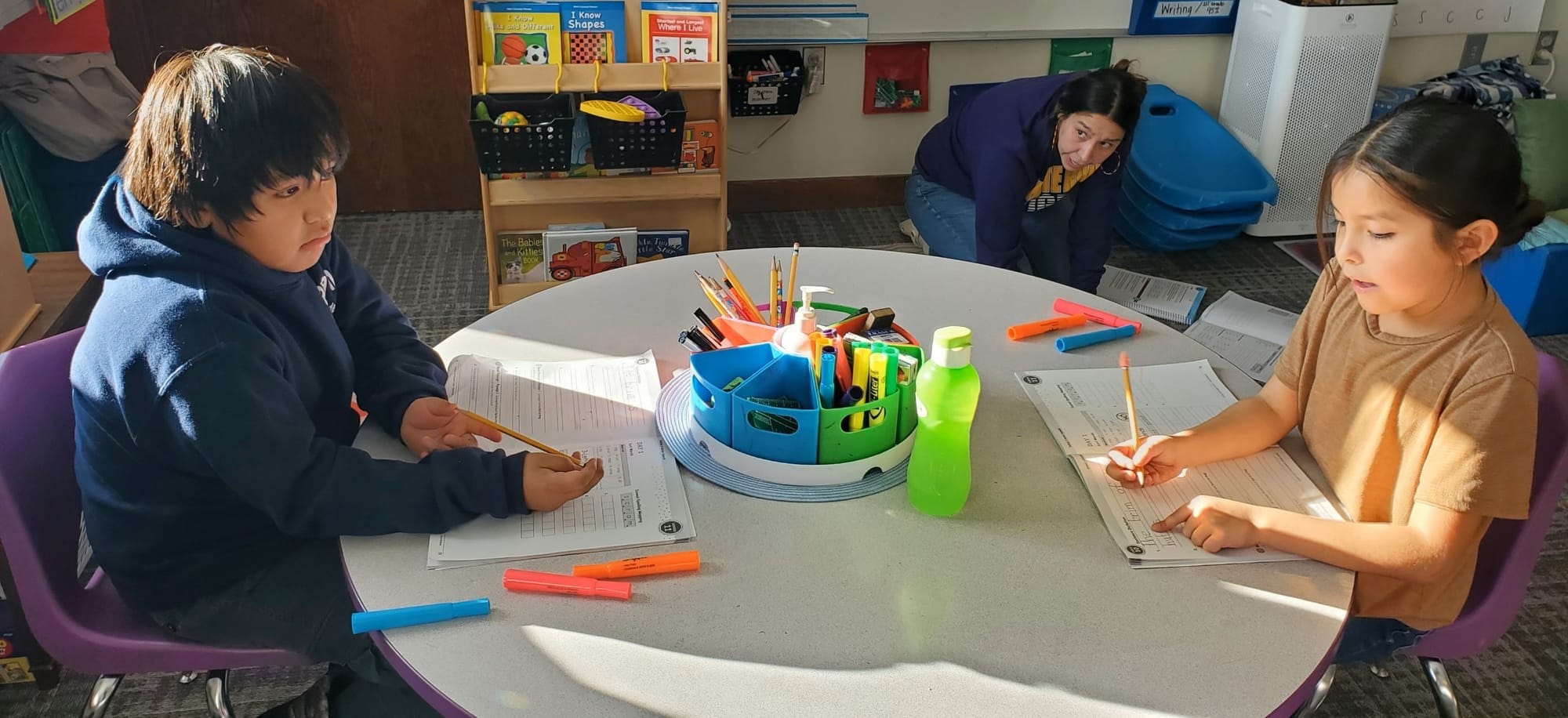 Students work on English assignments at a desk at school