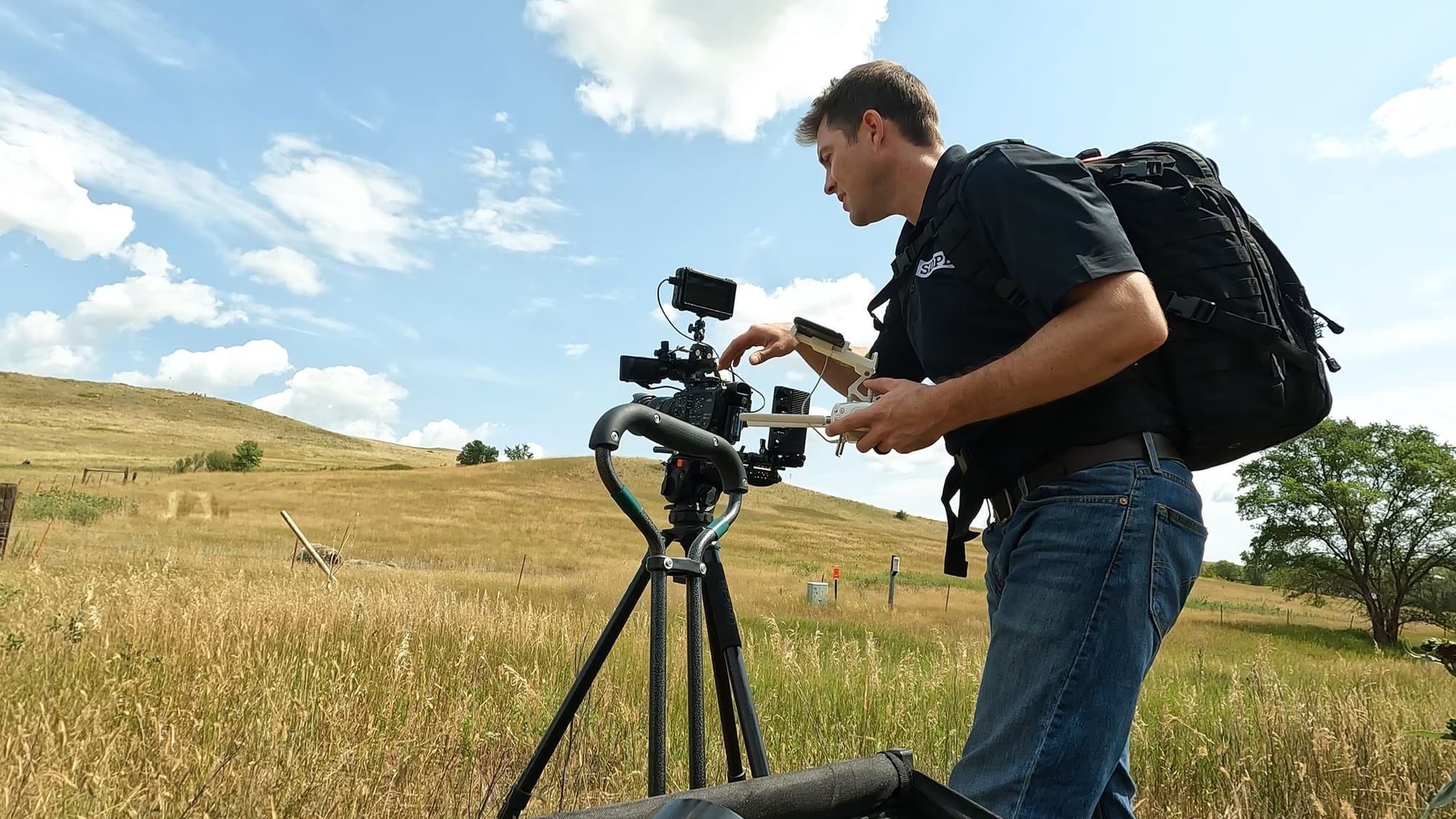 A man stands behind a video camera in a field in South Dakota