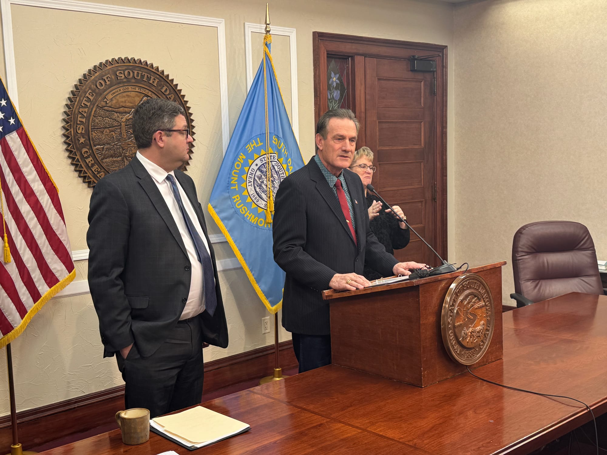 South Dakota Gov. Larry Rhoden stands behind a podium and speaks to the media in a conference room