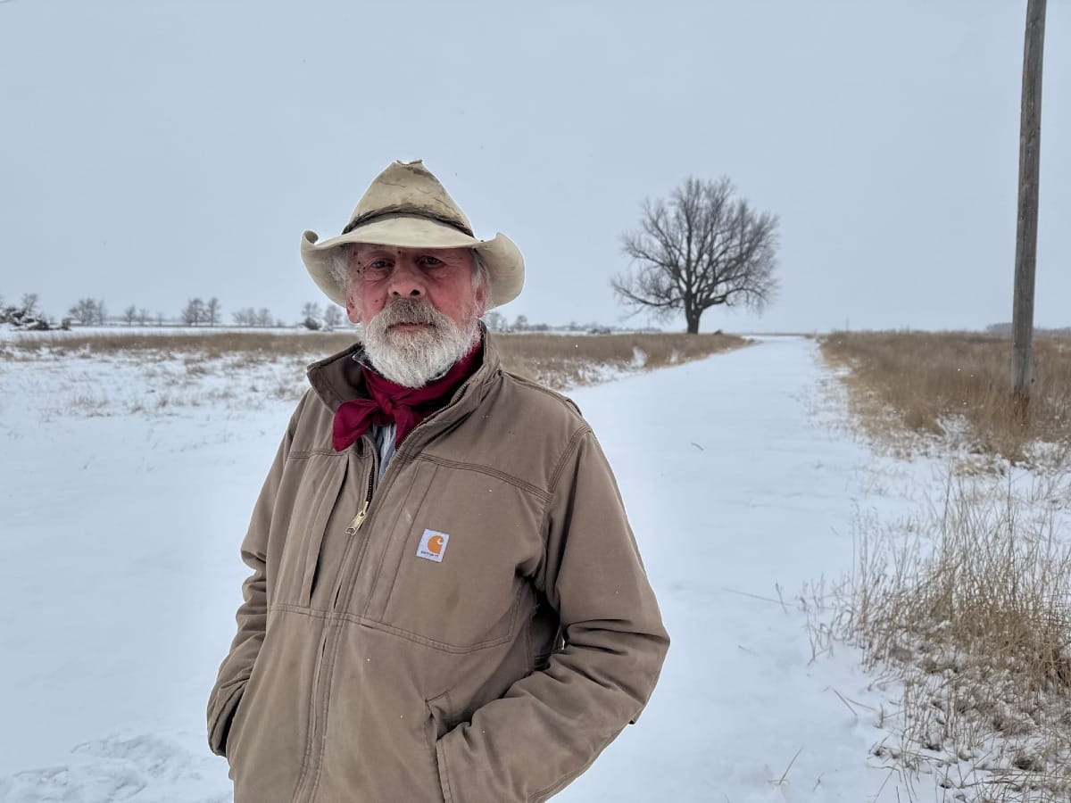 Tom Eiesland stands in a field filled with snow next to the proposed men's prison site.