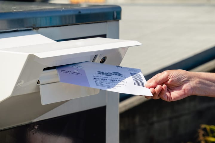 A person places their ballot in an election box