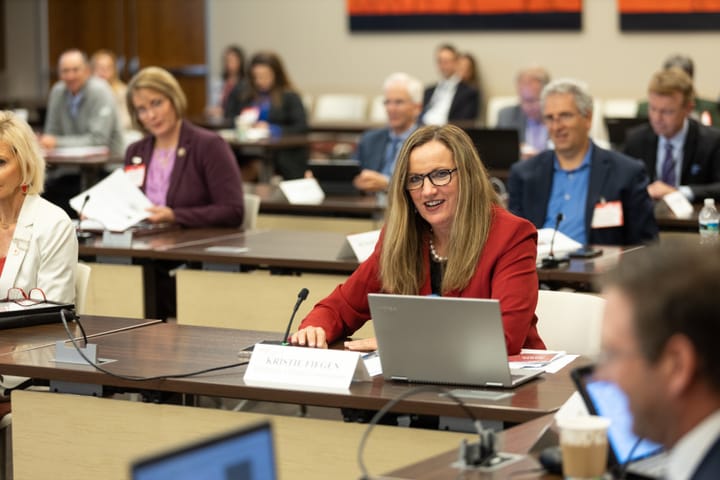 South Dakota Public Utilities Commission chairperson Kristie Fiegen sits at a table with a computer in a room full of people