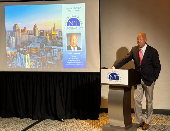 Former Secretary of Homeland Security Jeh Johnson stands behind a podium and speaks at the National Press Foundation 